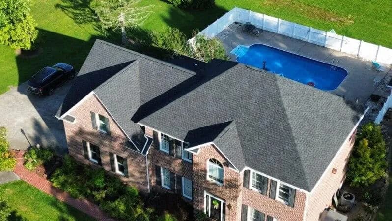 Drone view of a completed dark shingle roof on a brick home